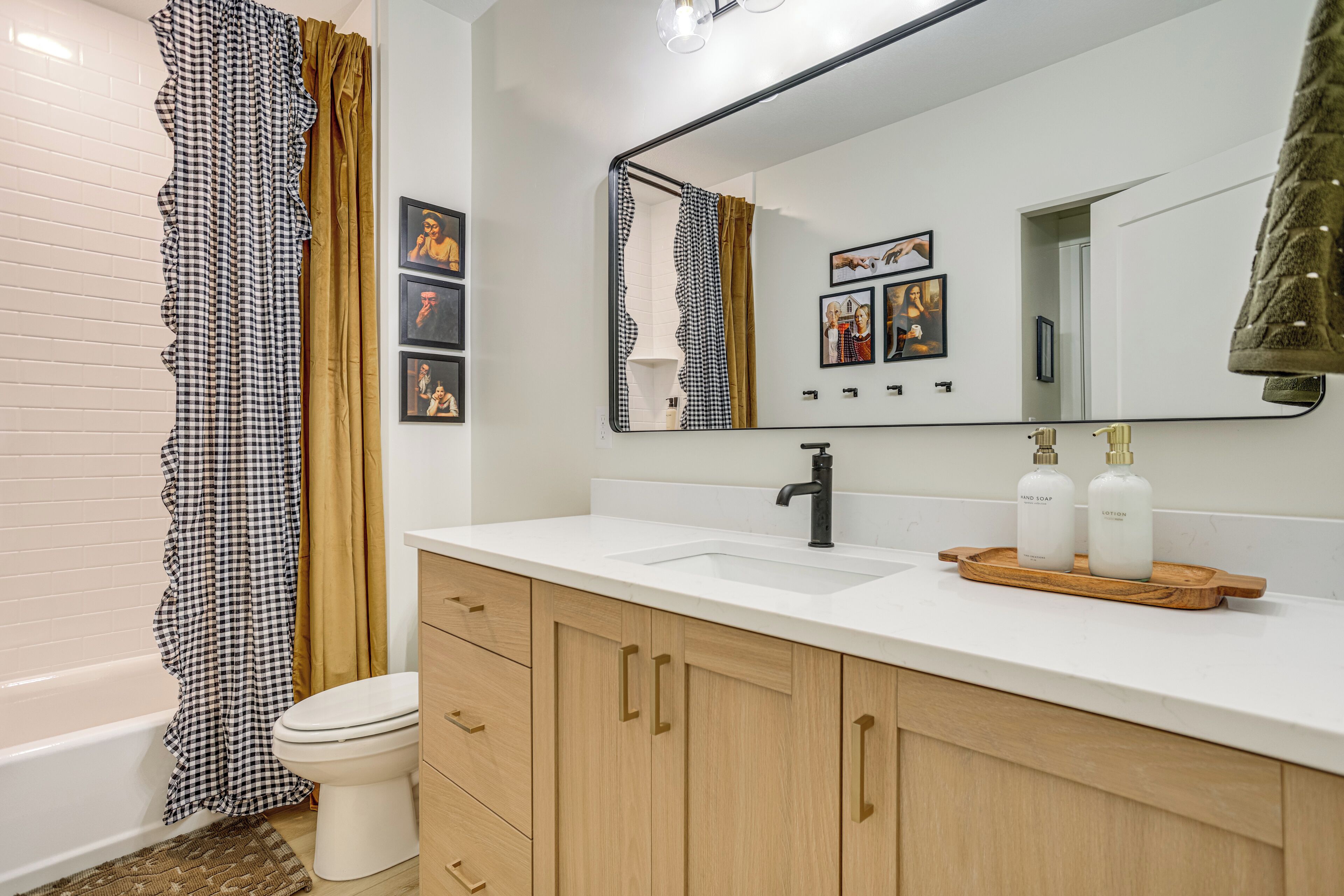 A bathroom with a white sink, a mirror, and a toilet. There are two bottles of hand soap on the sink.