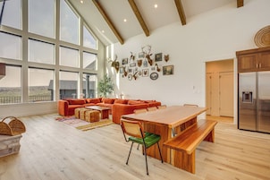 Uma sala de estar espaçosa com uma janela grande, uma mesa de jantar de madeira e uma cozinha moderna.