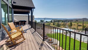 A wooden deck with outdoor furniture, a basketball court, and a scenic view of a lake and mountains. - Luxury Bear Lake Getaway w/ Sports Court & Hot Tub (Garden City)