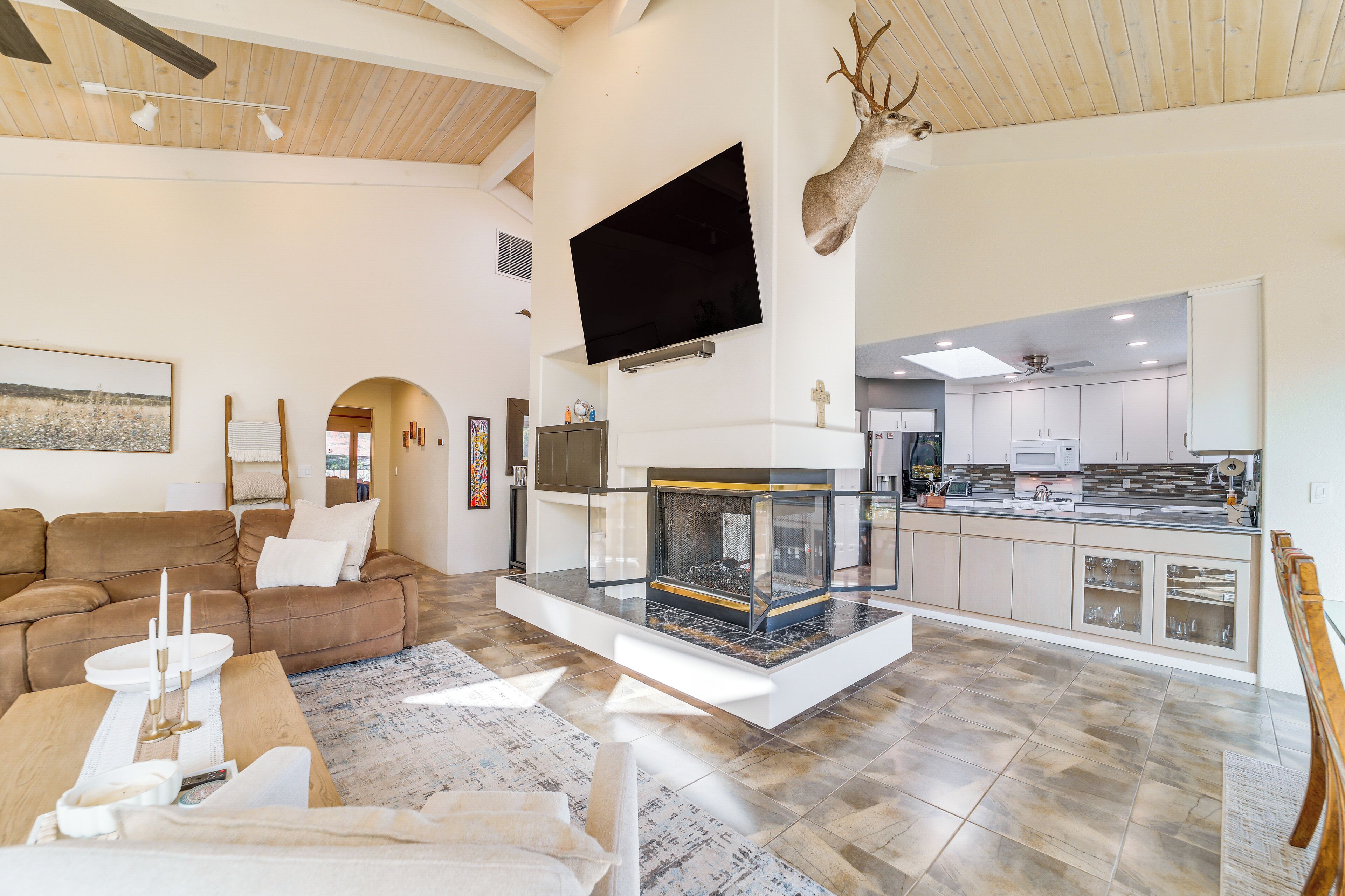 A modern living room with a fireplace, a mounted TV, and a deer head decoration.
