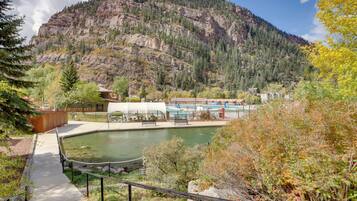 A mountain landscape with a swimming pool, a pathway, and a building with a white roof.