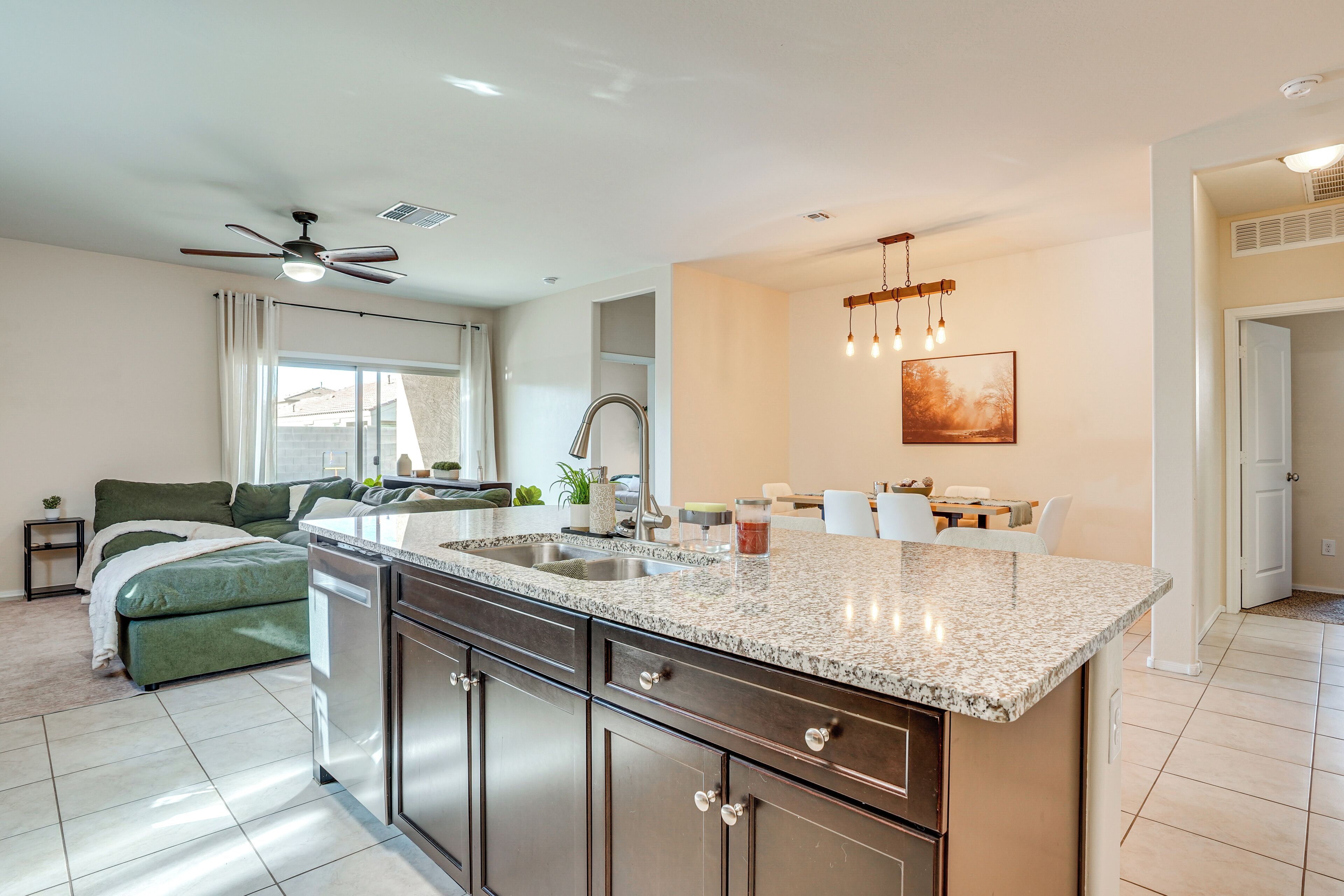 A modern kitchen with a granite countertop, stainless steel cabinets, and a dining area with a table and chairs.