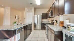 A modern kitchen with stainless steel appliances, granite countertops, and dark cabinetry. - Fenced Yard + Outdoor Games: Buckeye Home! (Buckeye)