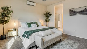 A bedroom with a bed, bedside tables, a ceiling fan, and two potted plants. - Fenced Yard + Outdoor Games: Buckeye Home! (Buckeye)