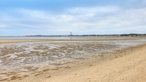 A beach with a sandy shore, a distant city skyline, and overcast sky. - Beach & Pool 318 sqf Cozy Condo East End P-town (Provincetown)