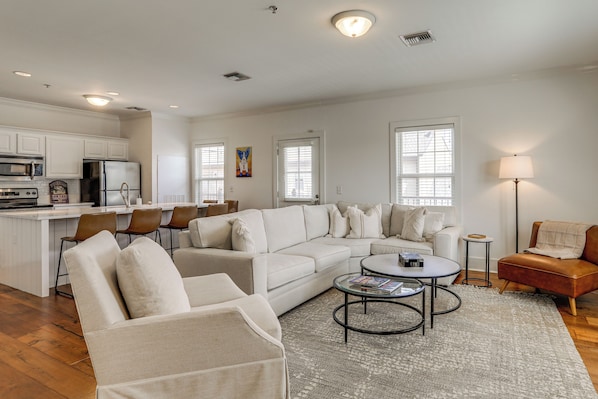 A modern living room with a sectional sofa, a coffee table, and a dining area with chairs.