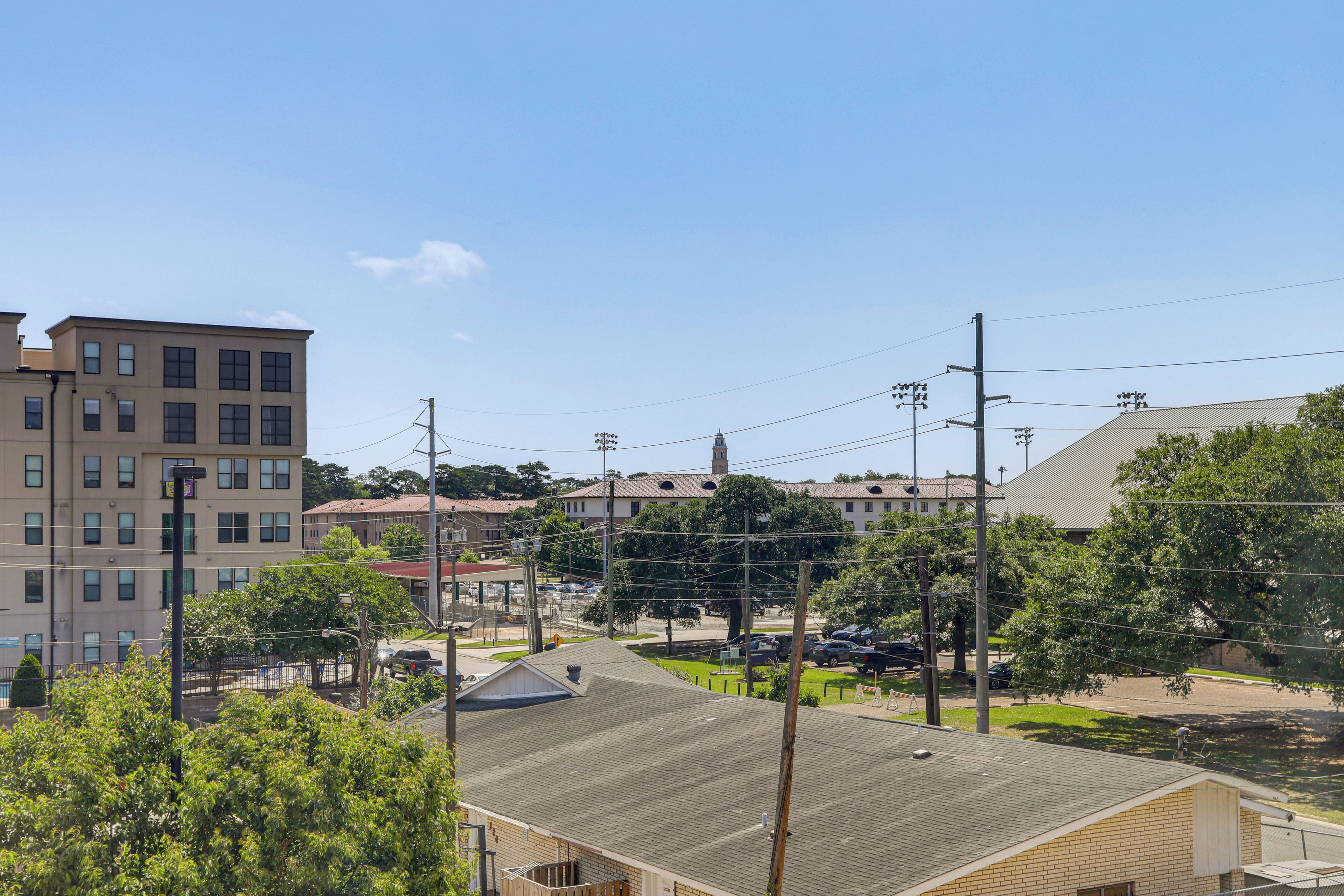 A multi-story building with a flat roof, surrounded by trees and power lines.
