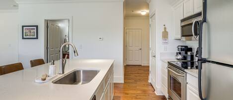 A kitchen with a large island, stainless steel appliances, and wooden flooring.