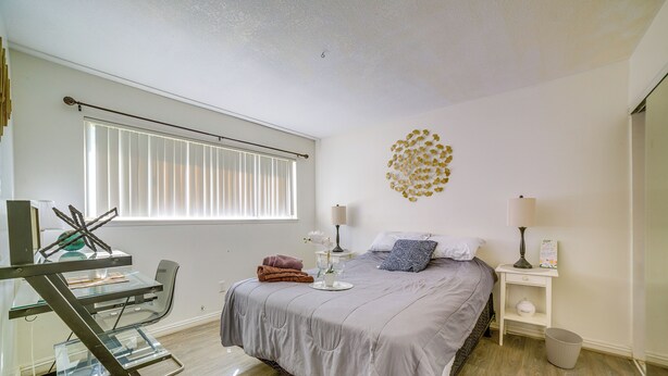 A bedroom with a bed, bedside tables, a desk, and a window with blinds. - Family Gem w/ Pet-friendly Yard! 8 Mi to Riverside (Moreno Valley)