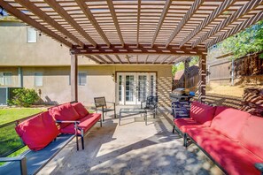 Eine Terrasse im Freien mit einer Pergola, roter Möbel und einem Grill.