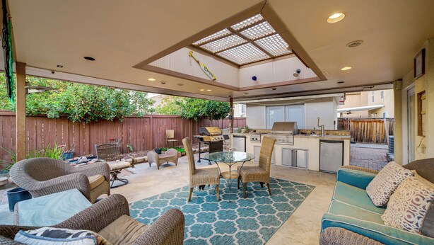 An outdoor patio with wicker furniture, a glass table, and a kitchen area. - Family Home 5 Mi to Dtwn Riverside & Hospital! (Riverside)