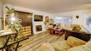 A living room with a fireplace, sofa, coffee table, and a television mounted on the wall. - Family Home 5 Mi to Dtwn Riverside & Hospital! (Riverside)