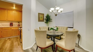 A dining area with a table, chairs, a chandelier, and a kitchen in the background. - Family Home 5 Mi to Dtwn Riverside & Hospital! (Riverside)