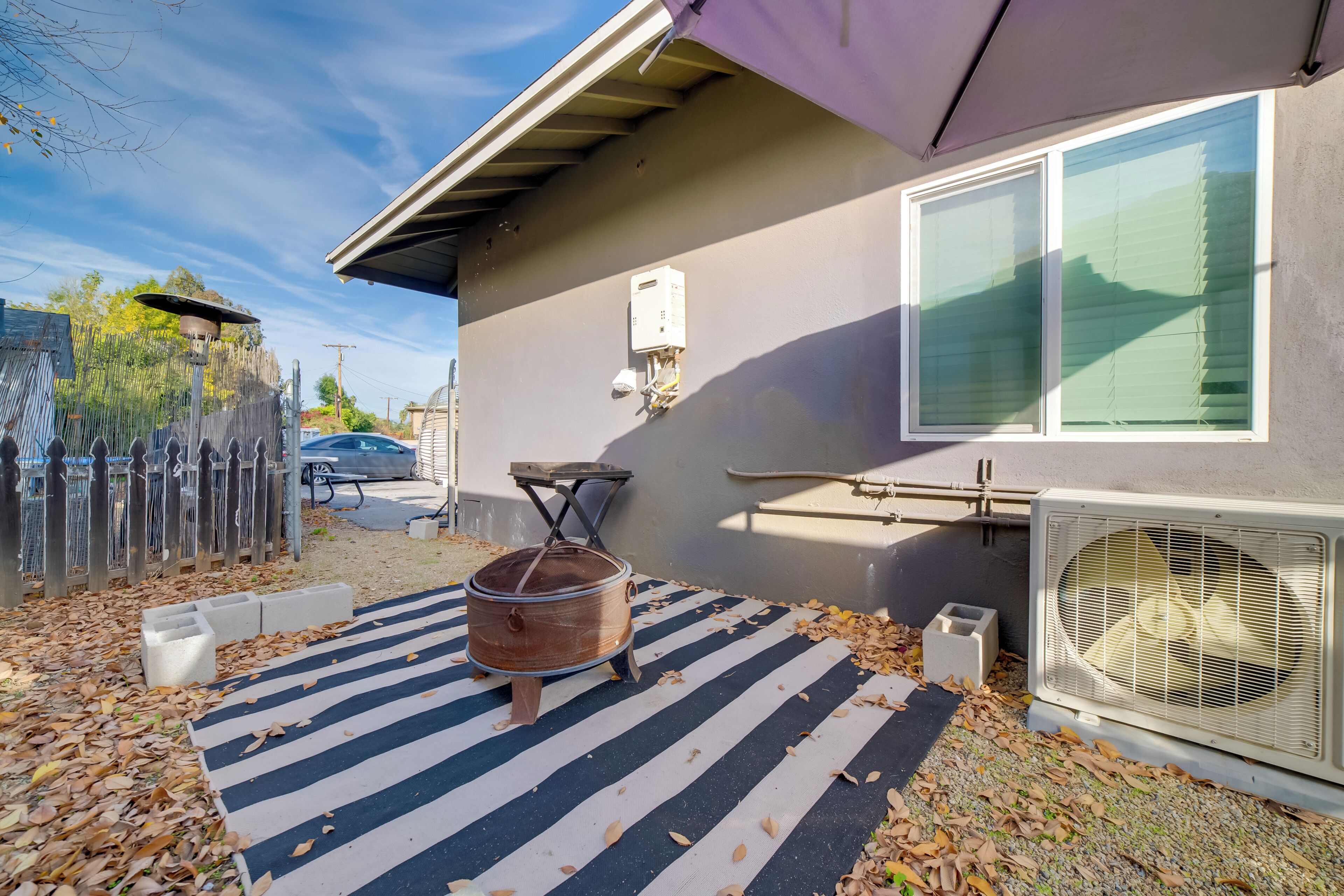 Une terrasse avec un tapis à rayures, un pot en cuivre, une fenêtre et un appareil de climatisation.