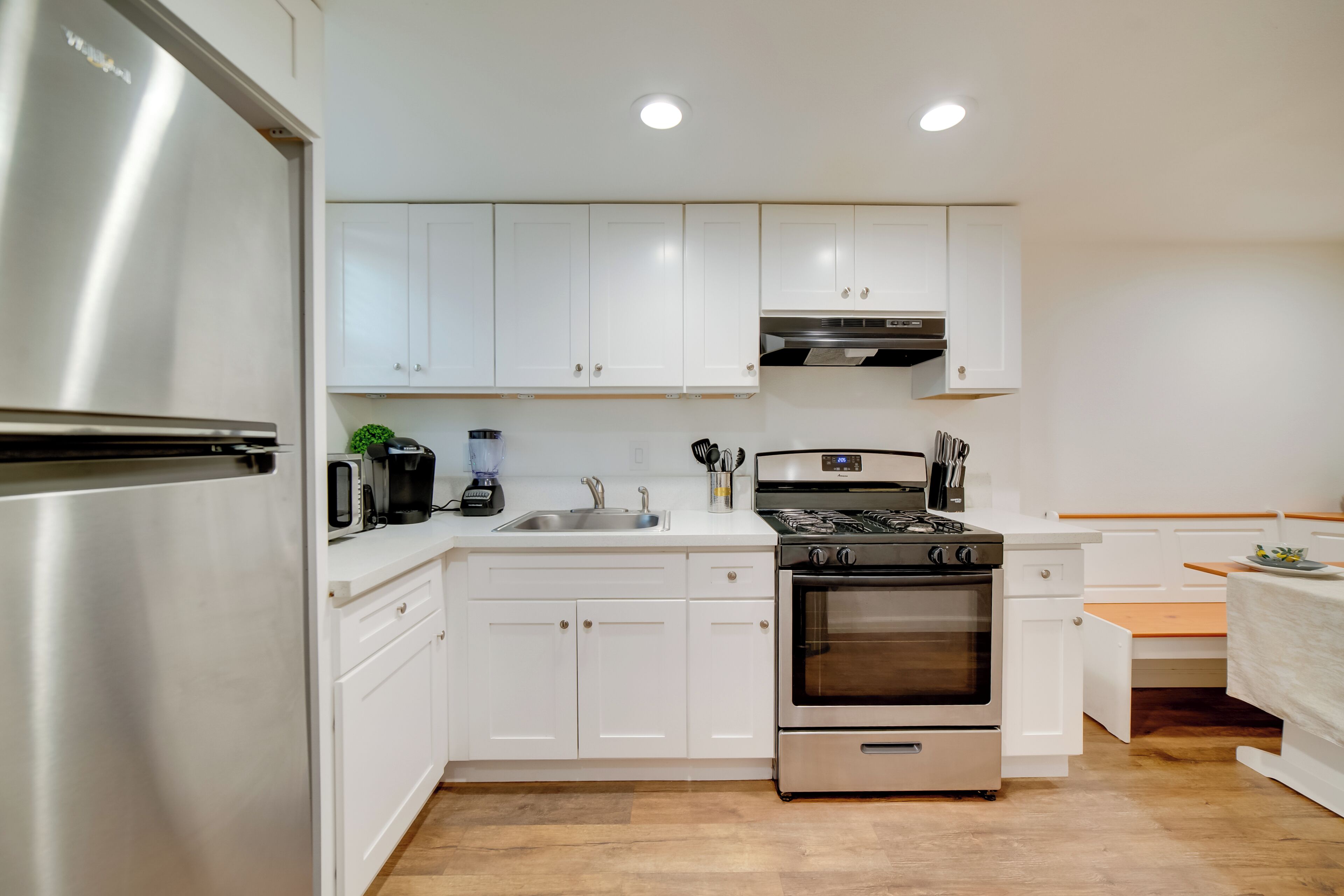 A modern kitchen with white cabinets, stainless steel appliances, a built-in oven, and a sink.