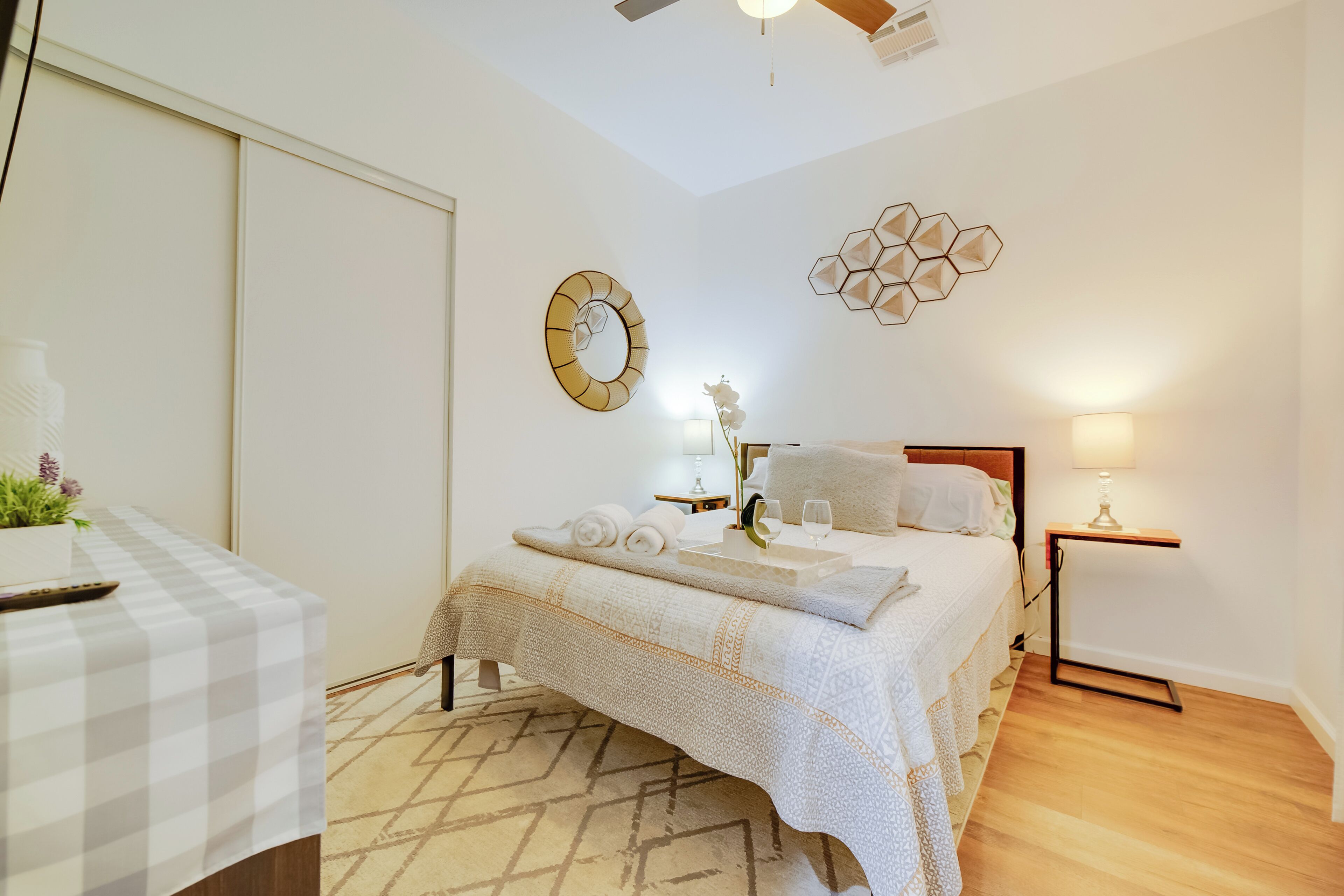 A bedroom with a bed, bedside tables, a wall clock, and a decorative wall piece.