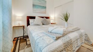 A bedroom with a bed, bedside tables, a nightstand, a plant, and a painting on the wall. - 2 Mi to Dtwn Riverside & Hospital! Family Retreat (Riverside)