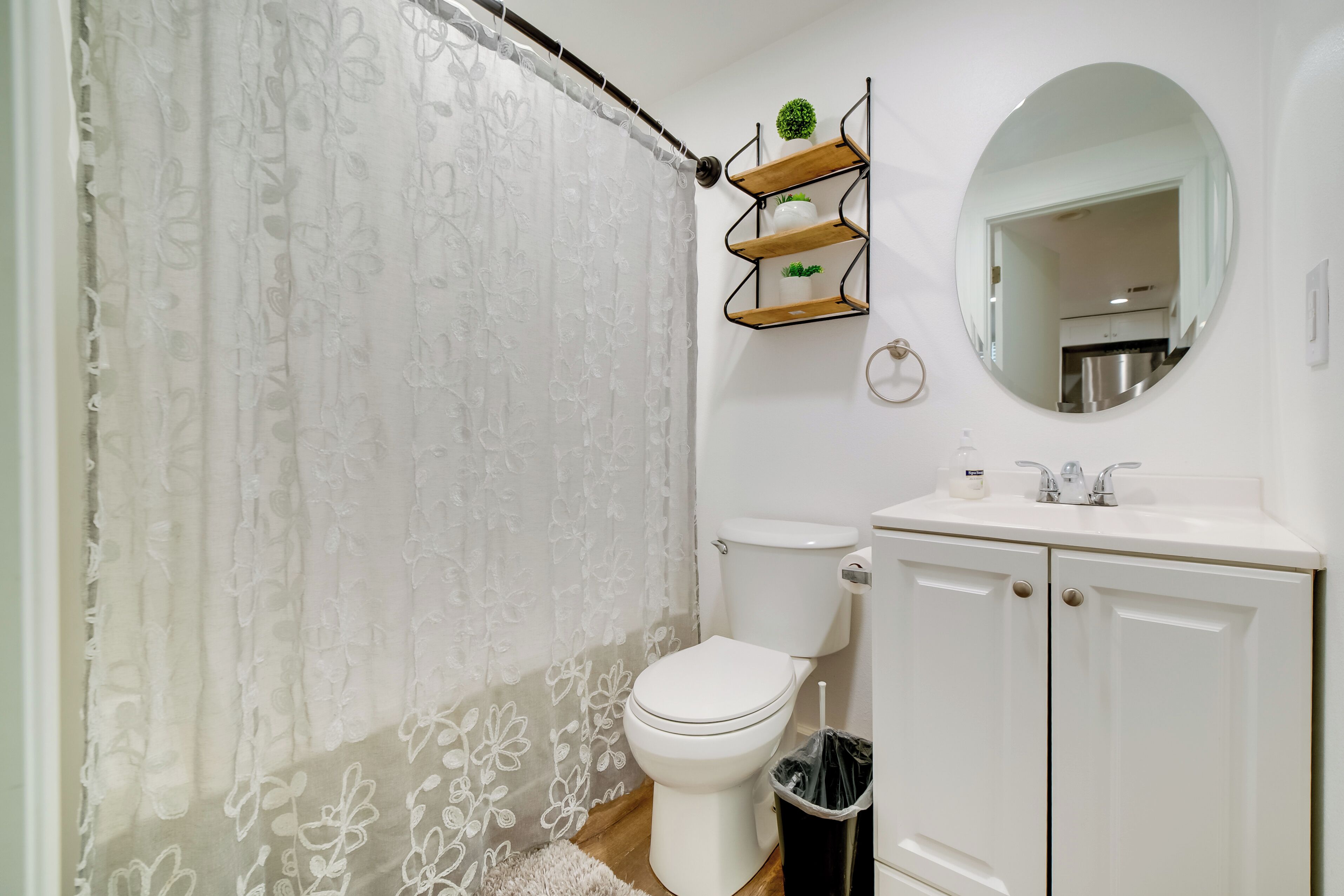 Ein Badezimmer mit Toilette, Waschbecken, Spiegel und Duschvorhang.