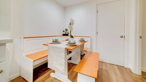 A small, clean room with a wooden bench, a table with a white tablecloth, and a door. - 2 Mi to Dtwn Riverside & Hospital! Family Retreat (Riverside)