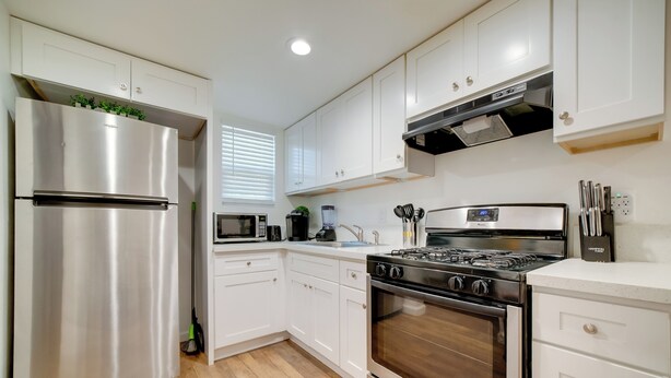 A modern kitchen with white cabinets, stainless steel appliances, and a wood floor. - 2 Mi to Dtwn Riverside & Hospital! Family Retreat (Riverside)