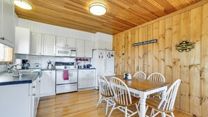 A kitchen with white cabinets, a wooden ceiling, and a dining table with white chairs. - Family Friendly! Secluded Worcester Haven w/ Deck (Worcester)