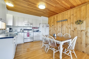 A kitchen with white cabinets, a wooden ceiling, and a dining table with white chairs. - Family Friendly! Secluded Worcester Haven w/ Deck (Worcester)