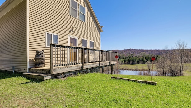 A two-story wooden house with a porch, a bear statue, and a pond in the background. - Family Friendly! Secluded Worcester Haven w/ Deck (Worcester)