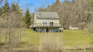 A two-story house with a balcony, surrounded by trees and a grassy area. - Family Friendly! Secluded Worcester Haven w/ Deck (Worcester)