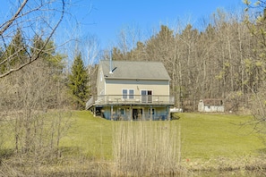 A two-story house with a balcony, surrounded by trees and a grassy area. - Family Friendly! Secluded Worcester Haven w/ Deck (Worcester)