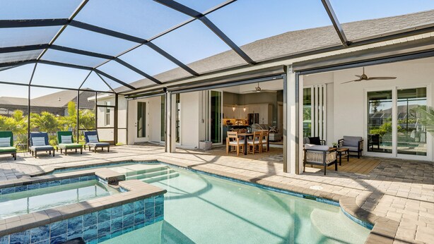 Una piscina cubierta al aire libre con zona de patio, juego de comedor y ventilador de techo.