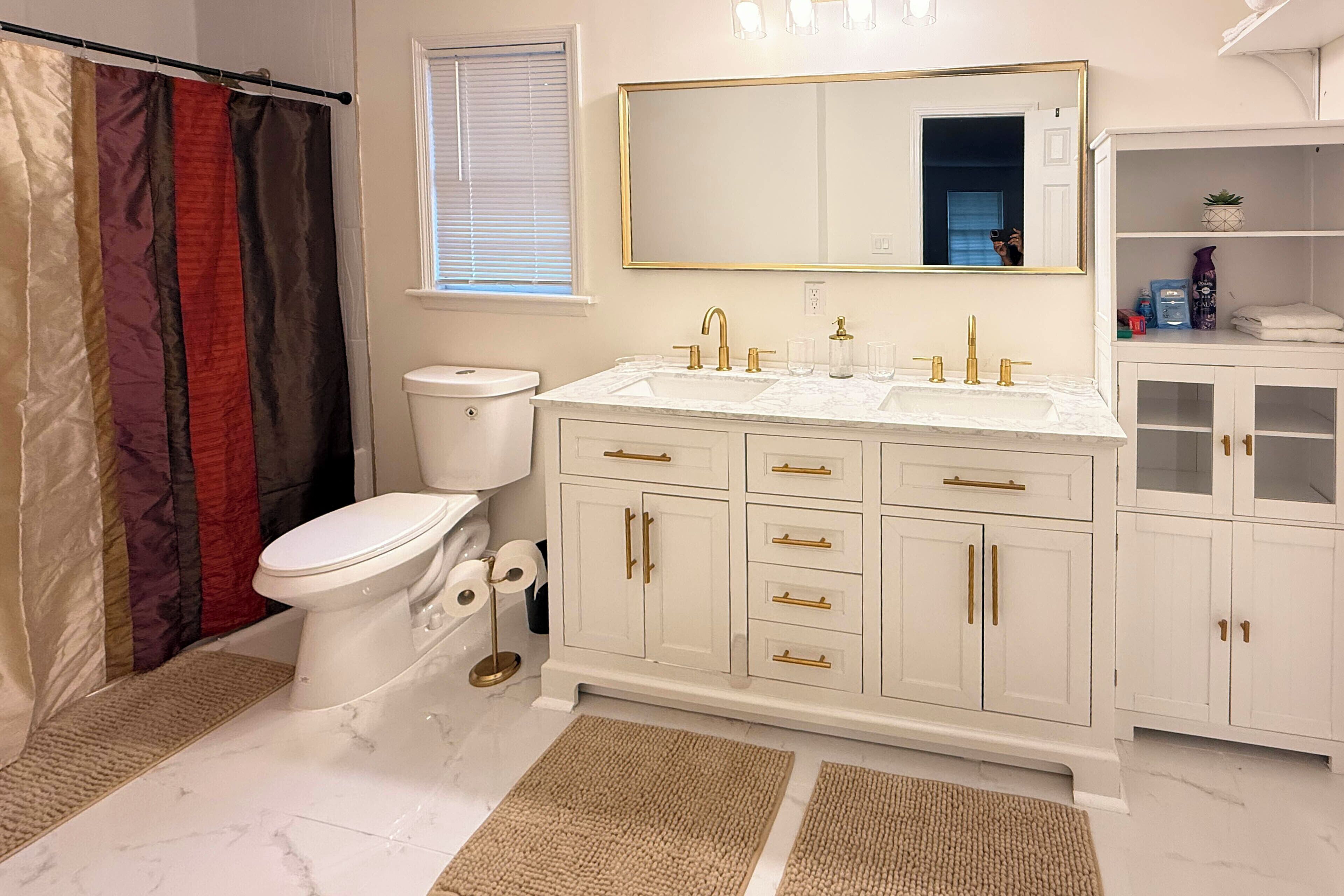 A bathroom with a toilet, sink, and mirror.