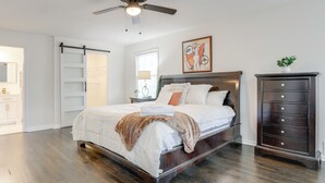 Ein Schlafzimmer mit Bett, Schminktisch, Deckenventilator, Fenster und Tür.