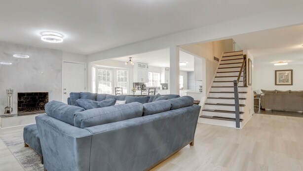 Ein modernes Wohnzimmer mit einem großen grauen Sofa, einem Kamin und einer Treppe, die zu einer anderen Ebene führt.