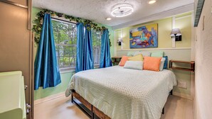 A bedroom with a bed, curtains, a painting, and a lamp.