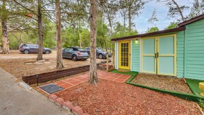 A small building with a yellow door, surrounded by trees and parked cars.