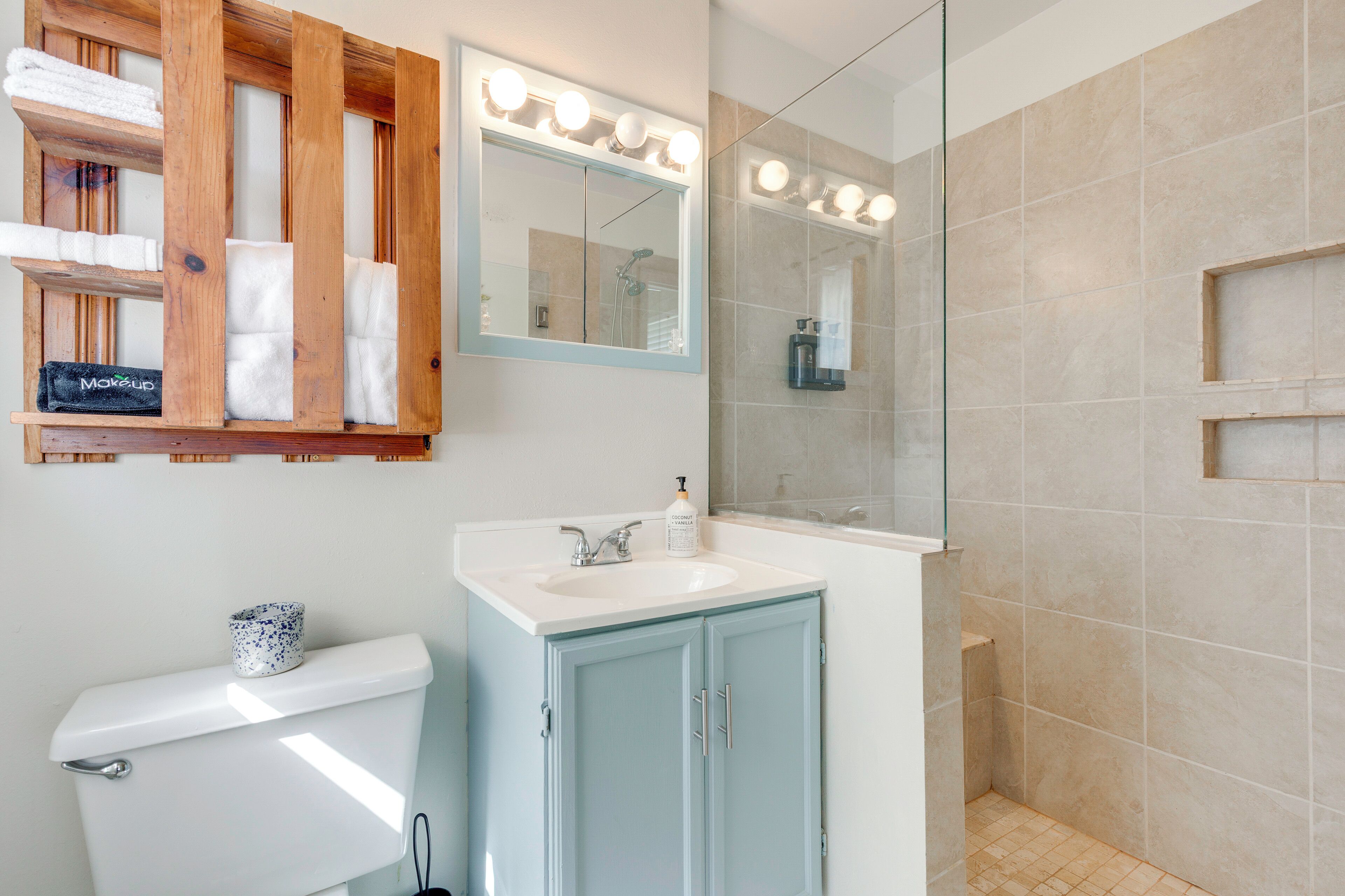 A bathroom with a toilet, a sink with a mirror, and a shower area.