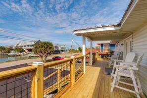 A wooden deck with a railing, outdoor seating, and a view of a marina. - Walk to Waves! Waterfront Beach House w/ Deck (Dauphin Island)