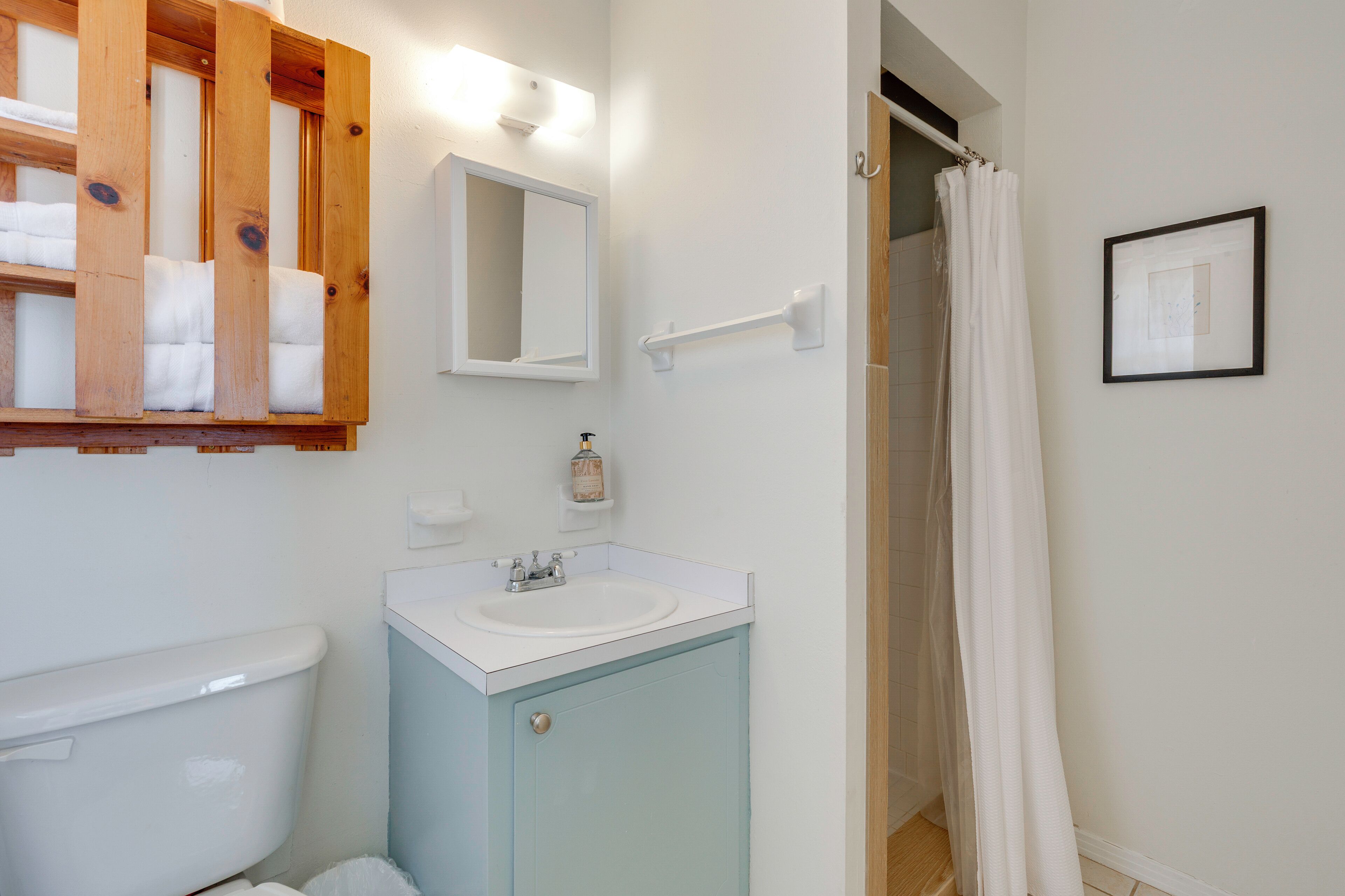 Un baño con inodoro, lavabo, espejo, toallero y cortina de ducha.