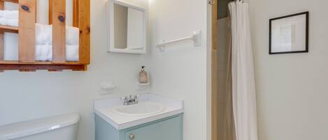 Un baño con inodoro, lavabo, espejo, toallero y cortina de ducha.