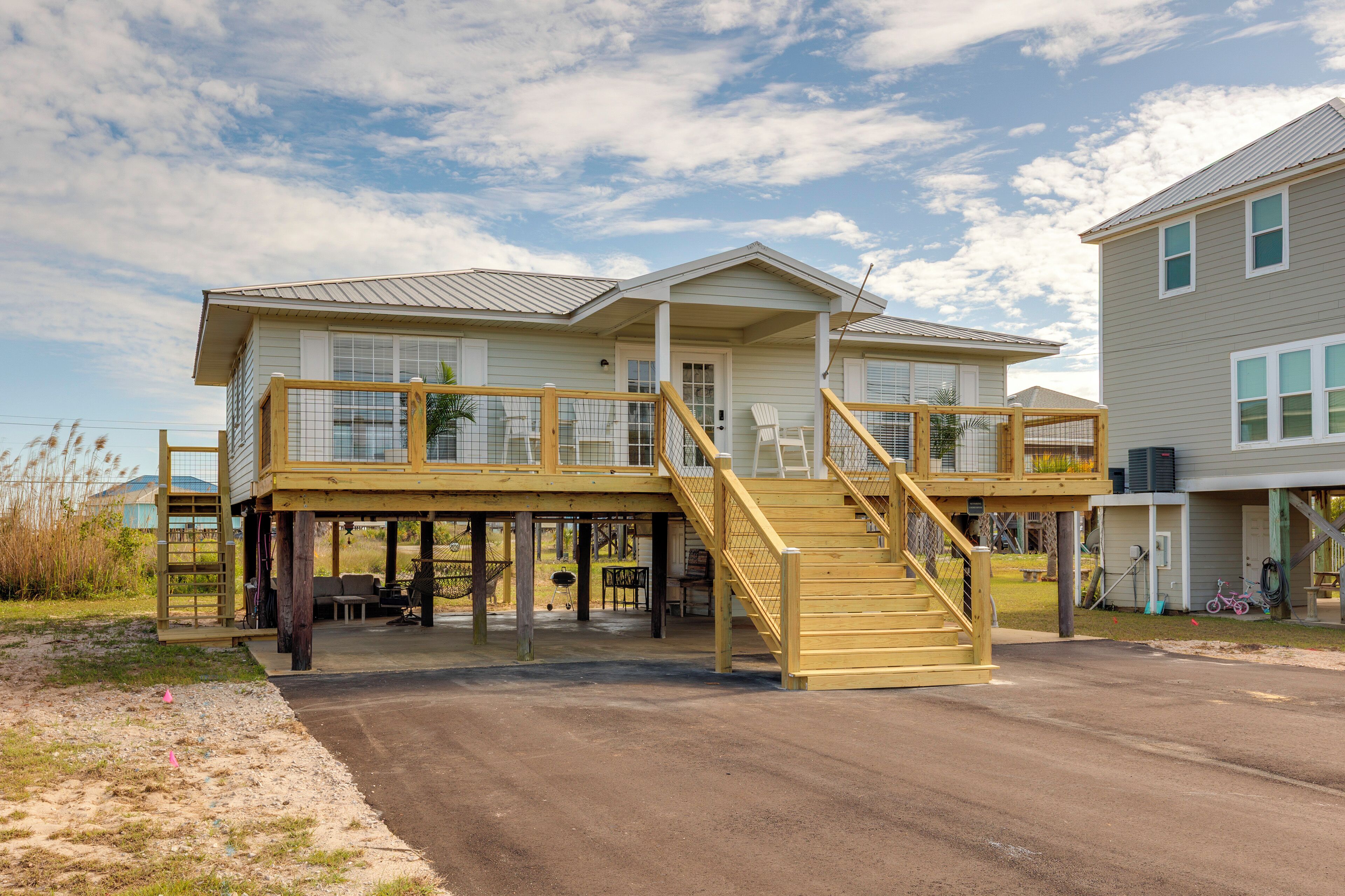 A two-story house with a wooden deck, a staircase, and a covered porch area.