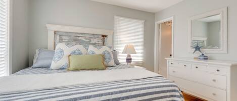 A bedroom with a bed, dresser, and a mirror.