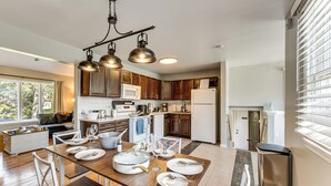 Una cucina moderna con mobili in legno, elettrodomestici in acciaio inossidabile e una zona pranzo con tavolo e sedie in legno.