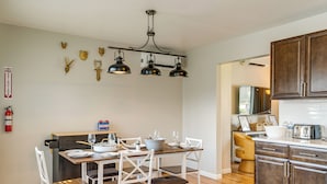 Una cucina con tavolo e sedie, una lampada a sospensione e mobili impiallacciati in legno.