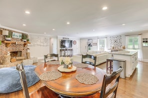 A spacious living area with a fireplace, a dining table with placemats, and a kitchen with a large island.