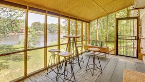 Un espace extérieur abrité, doté de grandes fenêtres, de tables et de chaises en bois.