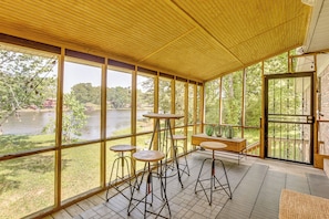 A covered outdoor area with large windows, wooden tables, and chairs.