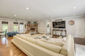 A spacious living room with a large white sofa, a fireplace, and a television.