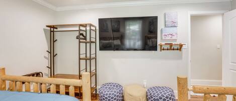A room with a bed, a wooden bench, a ladder, a TV, and a door.