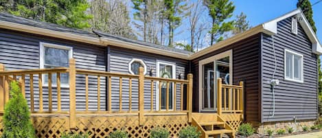 Een chalet met een houten terras, een overdekte veranda en een kleine voortuin met struiken.