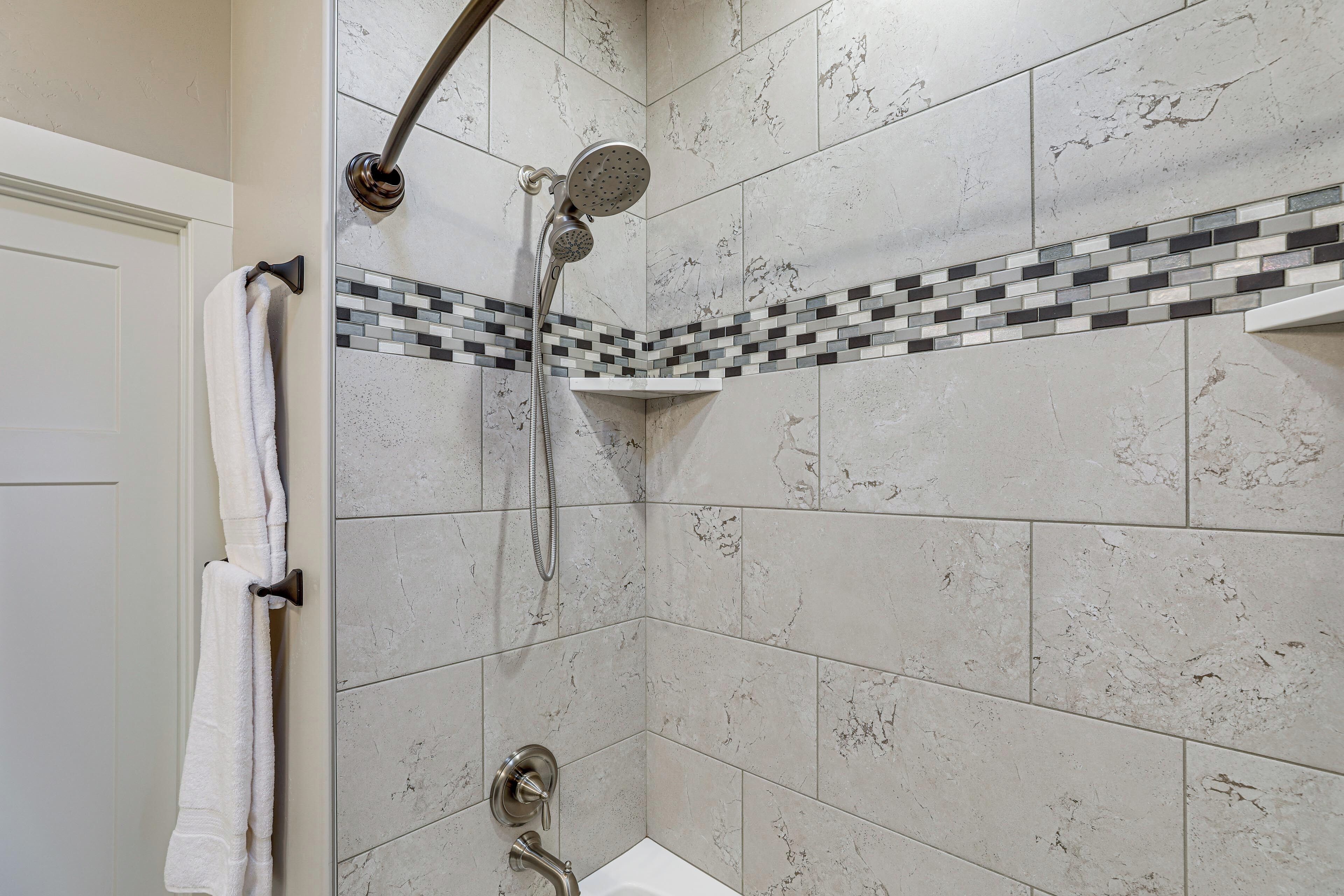 Un baño con ducha, paredes de azulejos y un perchero.